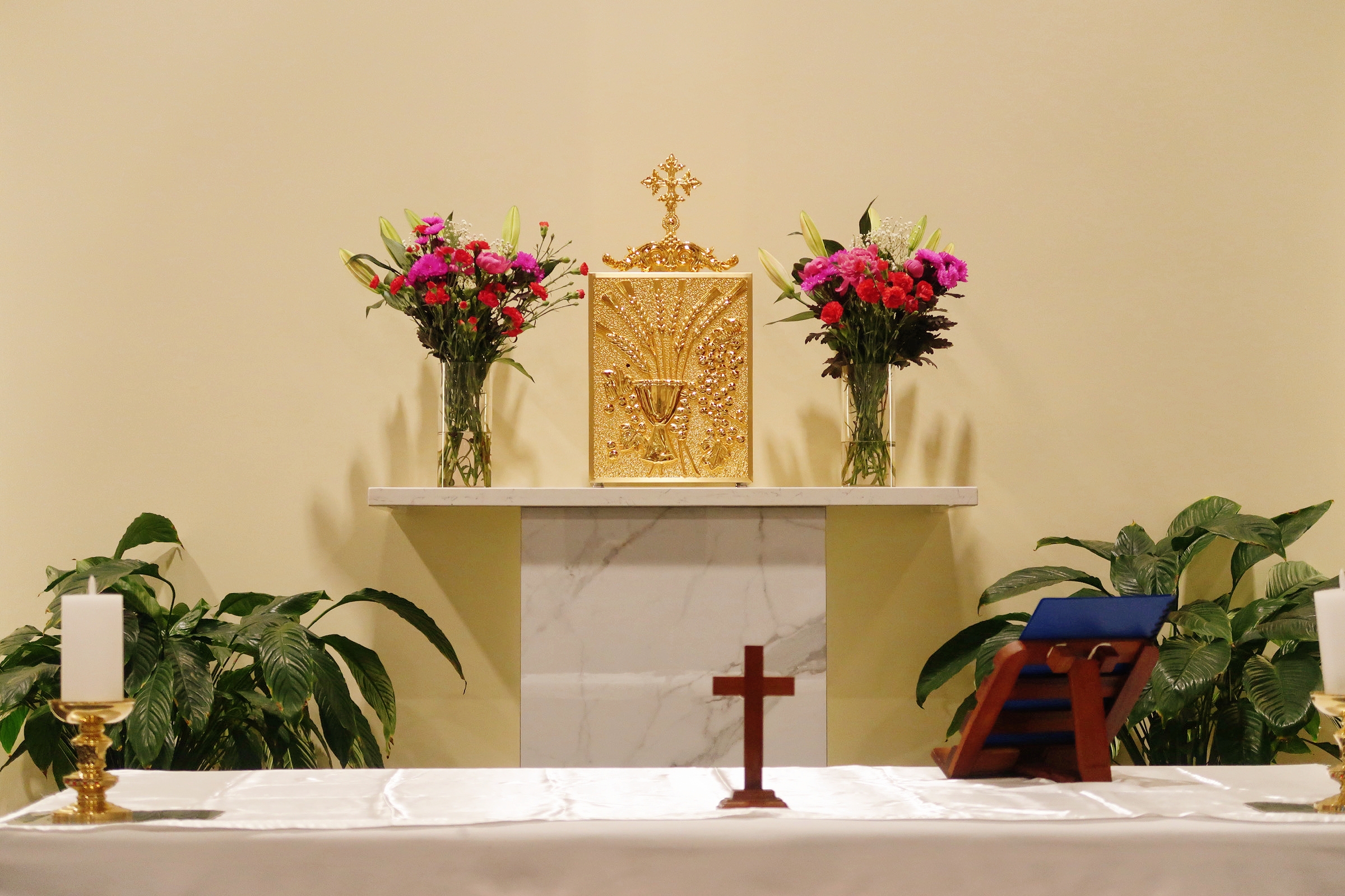 Golden tabernacle on the altar between two vases of flowers